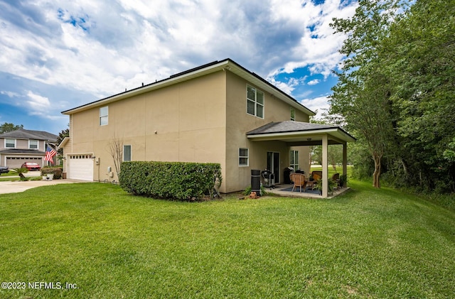 rear view of property featuring a patio, a yard, and a garage