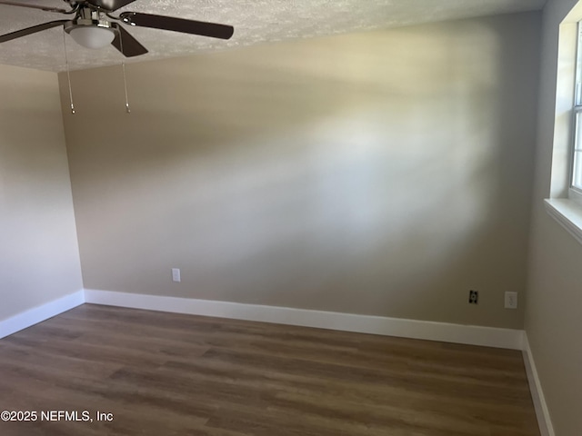 empty room with a textured ceiling, dark hardwood / wood-style flooring, and ceiling fan