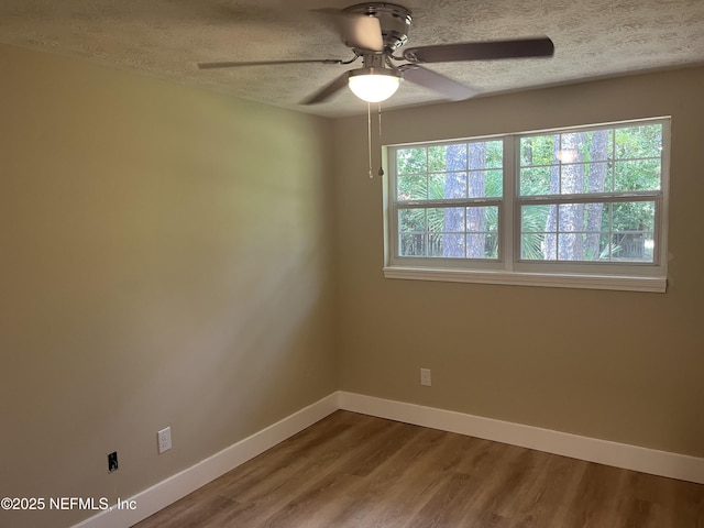 empty room featuring plenty of natural light, ceiling fan, wood-type flooring, and a textured ceiling