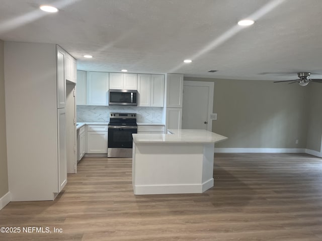 kitchen with decorative backsplash, white cabinetry, stainless steel appliances, and light hardwood / wood-style floors