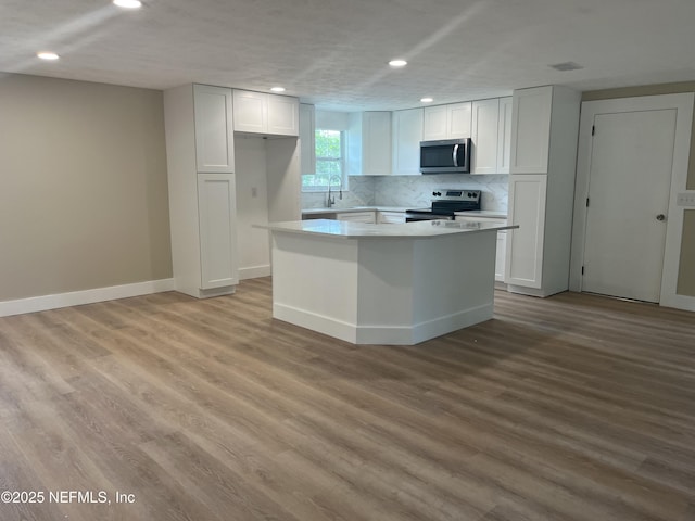 kitchen featuring light hardwood / wood-style flooring, white cabinets, stainless steel appliances, and a kitchen island