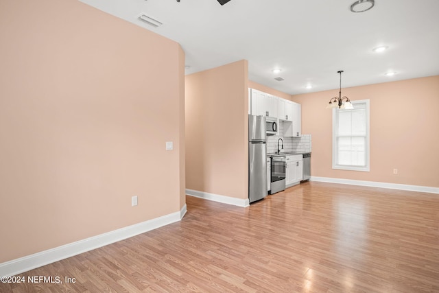 kitchen featuring white cabinetry, appliances with stainless steel finishes, backsplash, pendant lighting, and light hardwood / wood-style flooring