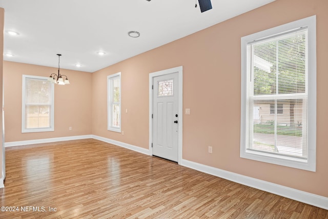 foyer entrance featuring ceiling fan with notable chandelier and light wood-type flooring