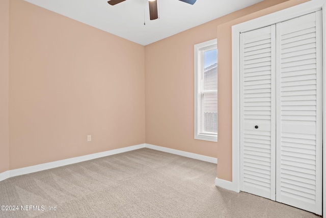 unfurnished bedroom featuring light carpet, a closet, and ceiling fan