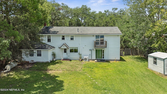 back of property with an outbuilding, a lawn, entry steps, fence, and a balcony