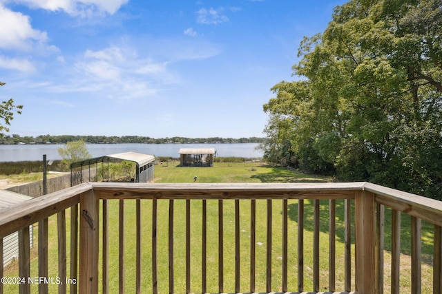 wooden terrace with an outbuilding, a water view, and a yard