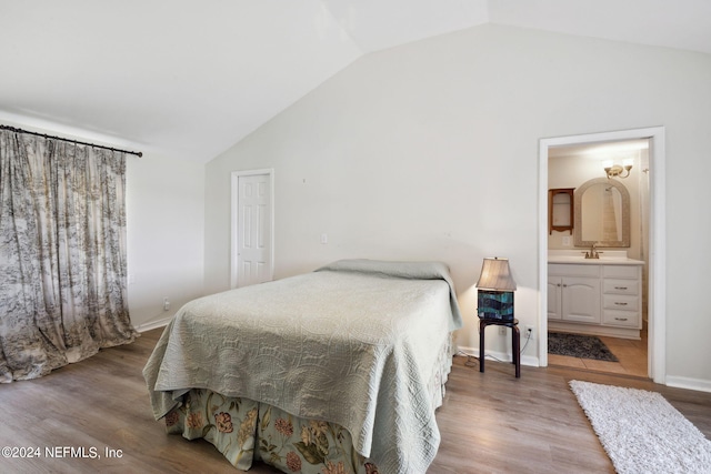 bedroom with wood-type flooring, sink, connected bathroom, and vaulted ceiling