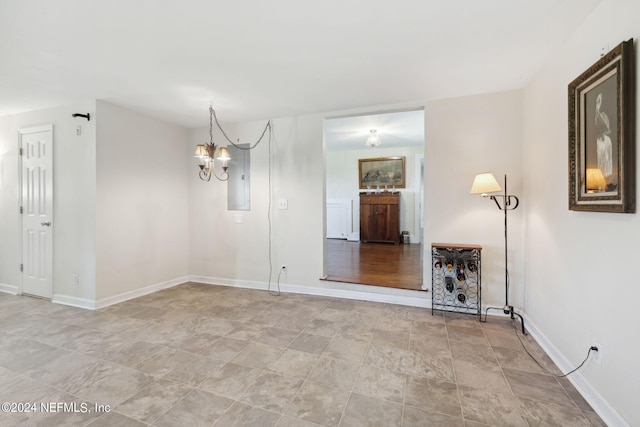 unfurnished room with baseboards, electric panel, and a notable chandelier