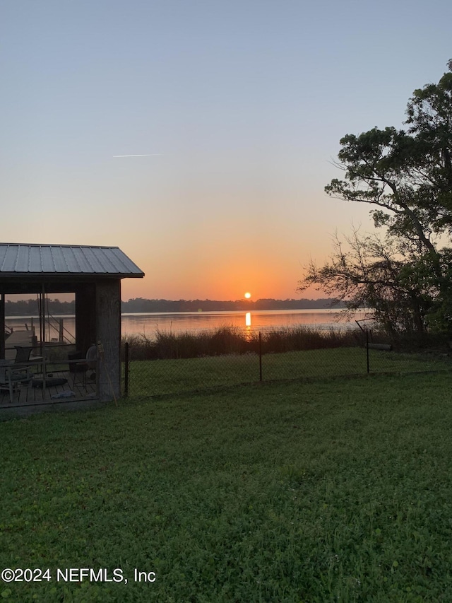 yard at dusk featuring a patio area and a water view