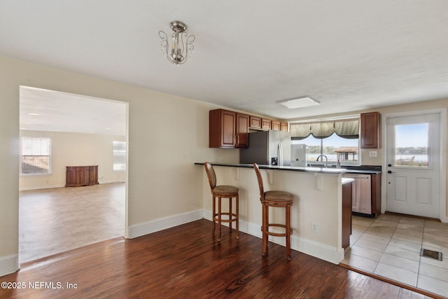 kitchen with a breakfast bar area, stainless steel appliances, visible vents, light wood-style flooring, and a sink