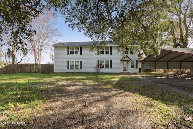 rear view of house featuring a detached carport, fence, driveway, and a lawn