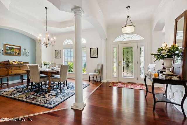 entrance foyer featuring an inviting chandelier, ornate columns, ornamental molding, a tray ceiling, and dark hardwood / wood-style flooring