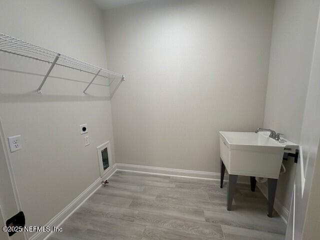 laundry area with baseboards, laundry area, electric dryer hookup, and light wood-style floors