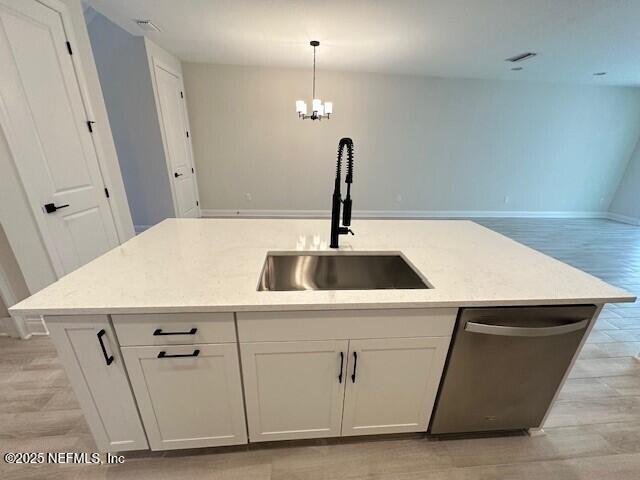 kitchen with stainless steel dishwasher, a sink, a center island with sink, and white cabinetry