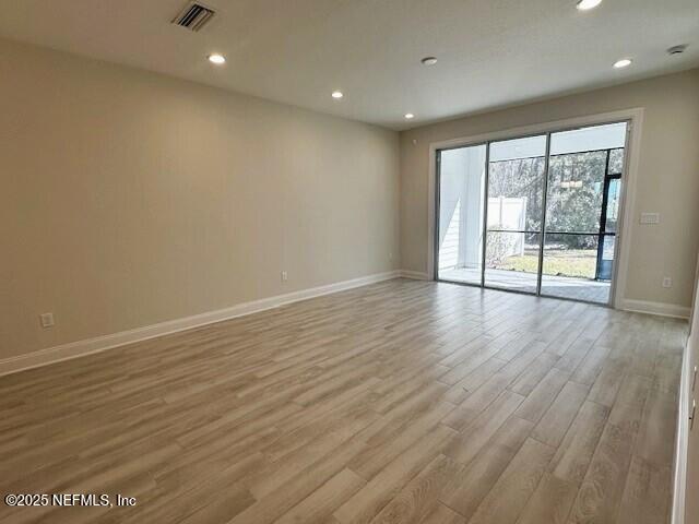 empty room with light wood-style floors, recessed lighting, visible vents, and baseboards