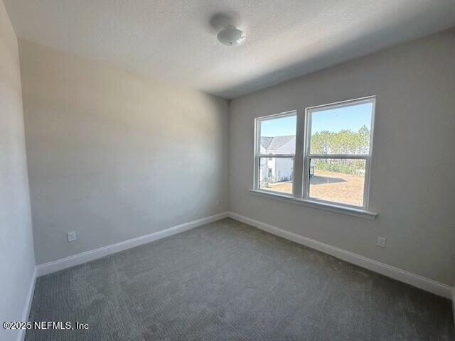 carpeted spare room featuring baseboards and a textured ceiling