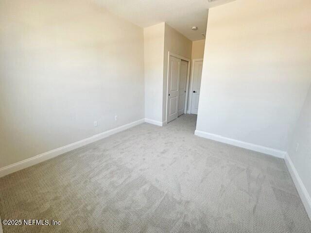 unfurnished room with baseboards and light colored carpet