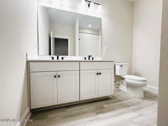 bathroom featuring baseboards, vanity, toilet, and wood finished floors