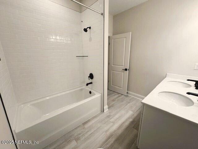 full bathroom with shower / bathtub combination, wood finished floors, a sink, and baseboards