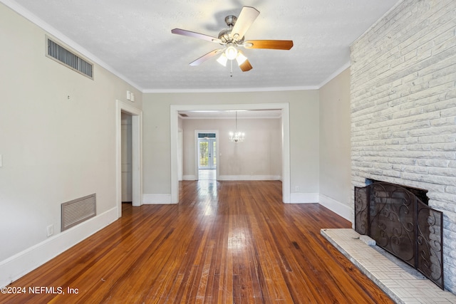 unfurnished living room featuring crown molding, hardwood / wood-style floors, a fireplace, a textured ceiling, and ceiling fan with notable chandelier