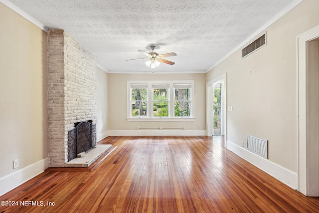 unfurnished living room featuring hardwood / wood-style flooring, crown molding, a textured ceiling, and a fireplace