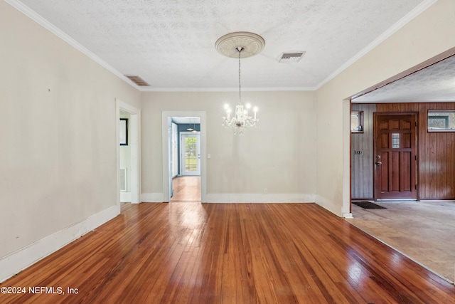 unfurnished dining area featuring crown molding, wood-type flooring, a chandelier, and a textured ceiling