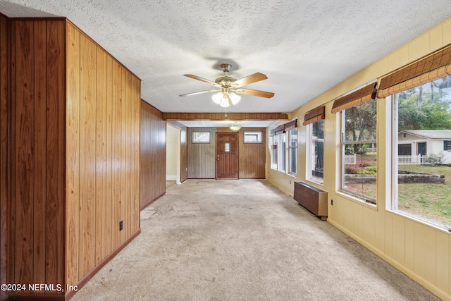 unfurnished sunroom featuring radiator heating unit and ceiling fan