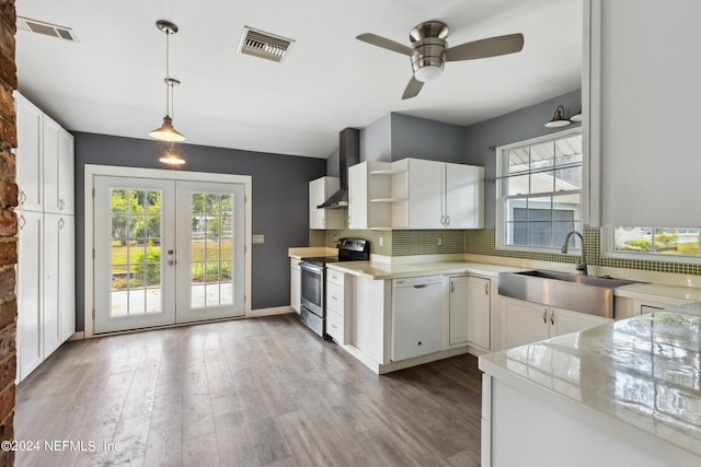 kitchen featuring stainless steel electric stove, pendant lighting, white cabinetry, backsplash, and wall chimney range hood