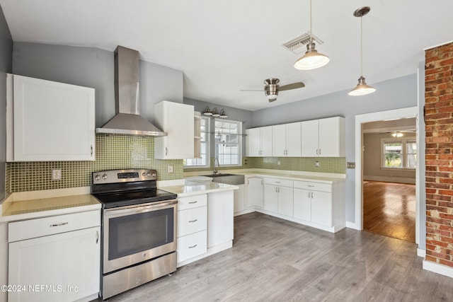 kitchen featuring electric stove, white cabinets, backsplash, and wall chimney range hood