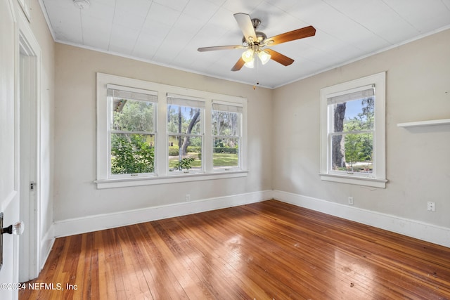 spare room with hardwood / wood-style floors, crown molding, a wealth of natural light, and ceiling fan