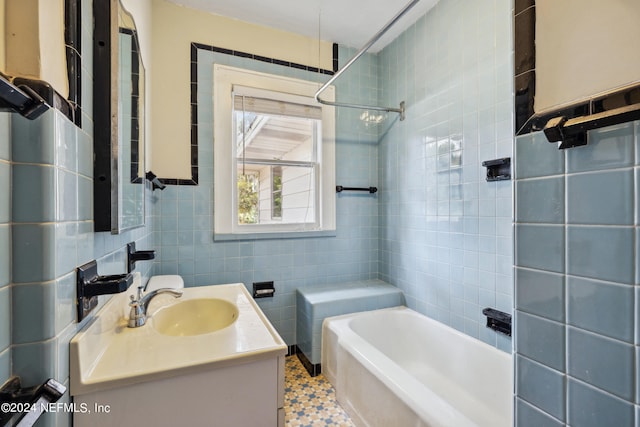 bathroom featuring tile patterned floors, vanity, tiled shower / bath combo, and tile walls