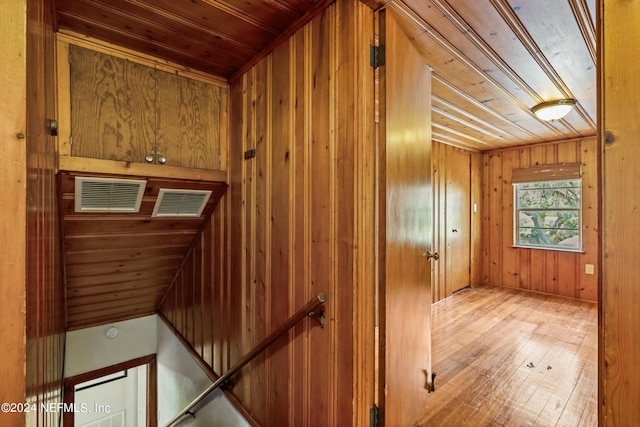 interior space with light hardwood / wood-style flooring, wooden walls, and wooden ceiling