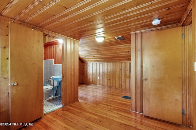 additional living space with wood ceiling, wooden walls, and light hardwood / wood-style floors