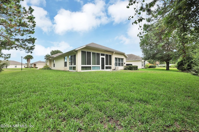 rear view of property featuring a yard and a sunroom