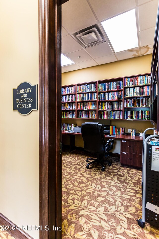 office space with a paneled ceiling and built in desk