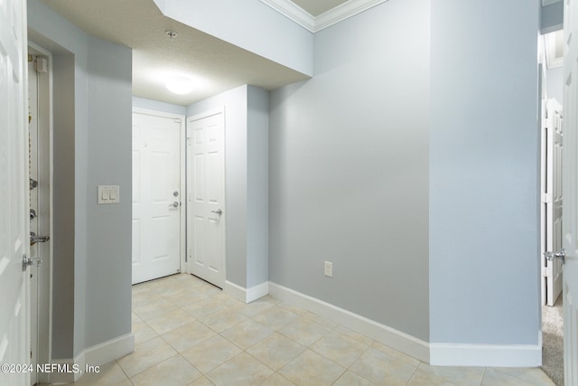 spare room with ornamental molding, a textured ceiling, and light tile patterned flooring