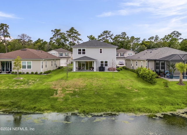 rear view of property with a water view, glass enclosure, and a lawn