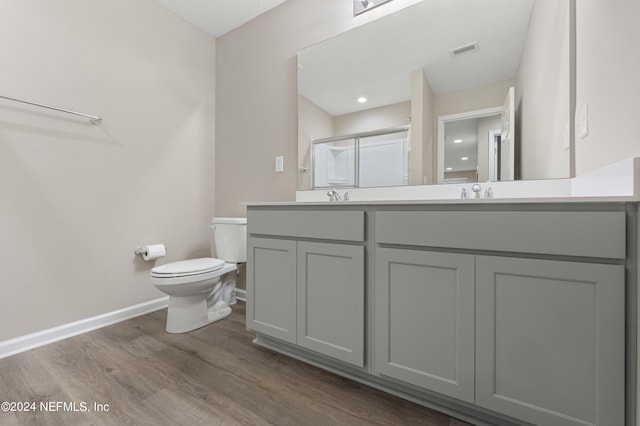 bathroom featuring hardwood / wood-style flooring, vanity, toilet, and a shower with door