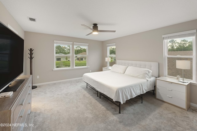 bedroom featuring multiple windows, ceiling fan, and light colored carpet