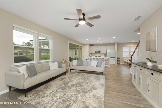 living room featuring ceiling fan, light hardwood / wood-style floors, and a healthy amount of sunlight