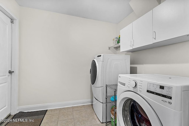 laundry area with cabinets, light tile patterned floors, and washer and clothes dryer