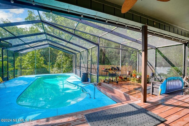 view of pool featuring a wooden deck and glass enclosure