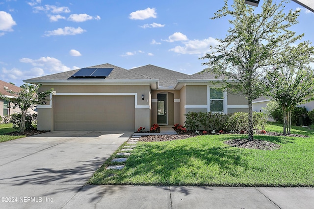 view of front of property featuring a front yard, driveway, roof mounted solar panels, and stucco siding