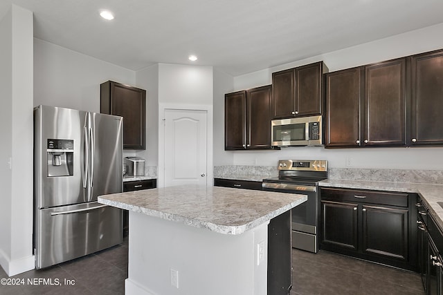 kitchen featuring a kitchen island, appliances with stainless steel finishes, light countertops, dark brown cabinets, and dark tile patterned floors