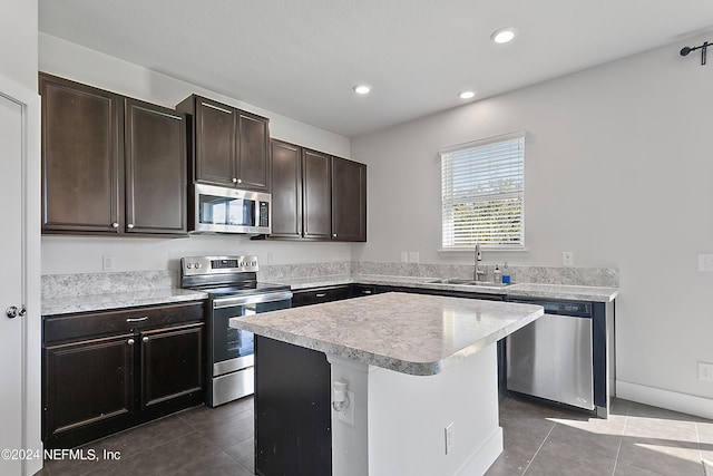 kitchen featuring a center island, light countertops, appliances with stainless steel finishes, a sink, and tile patterned floors