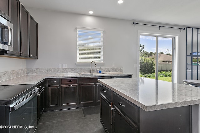 kitchen featuring a sink, a center island, light countertops, black electric range oven, and stainless steel microwave