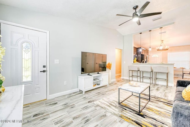 living room featuring lofted ceiling and ceiling fan with notable chandelier