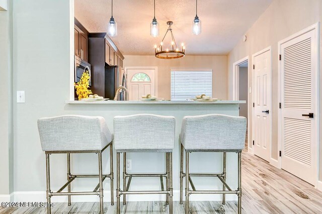 kitchen with a breakfast bar area, stainless steel appliances, kitchen peninsula, pendant lighting, and an inviting chandelier