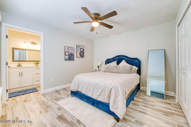 bedroom featuring ceiling fan, light hardwood / wood-style flooring, ensuite bathroom, and a closet