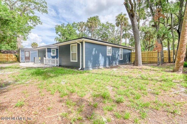 rear view of property with a yard and central air condition unit